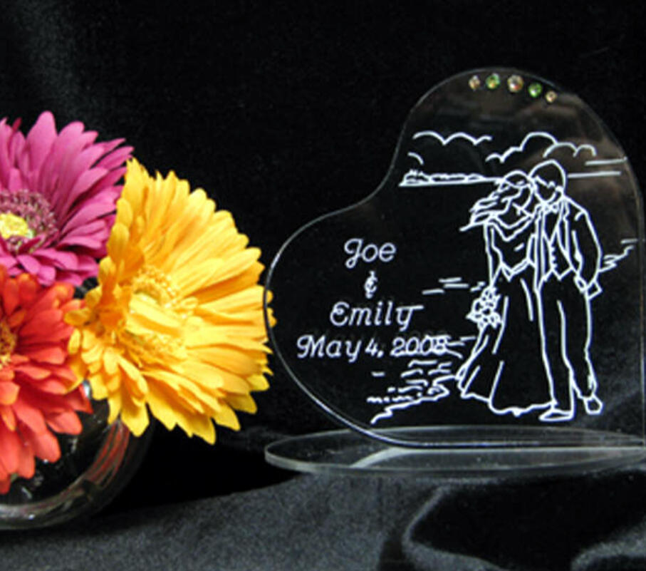 Custom engraved acrylic wedding cake topper personalized with names, date, and a design created with the couple.